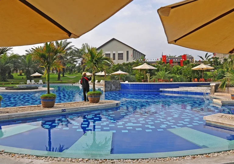 A bright resort swimming pool with palm trees and sun umbrellas in Da Nang