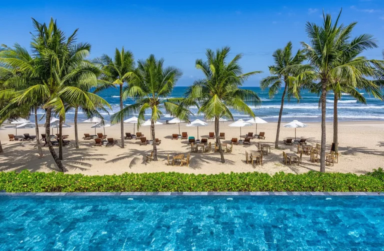 Palm trees, sun loungers and a pool facing the beach in Da Nang